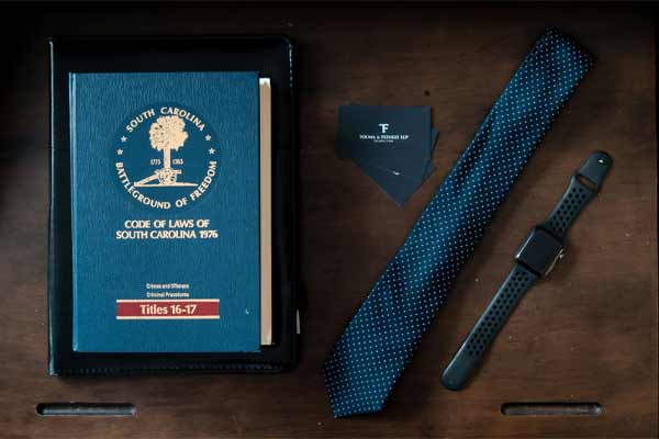 una corbata, un reloj, un libro de leyes y tarjetas de presentación en un escritorio en Touma Law Group
