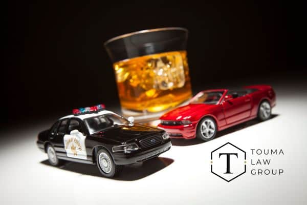 two toy cars in front of a glass of alcohol