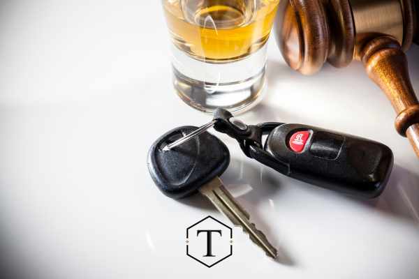 alcohol, a car key, and gavel on a white desk